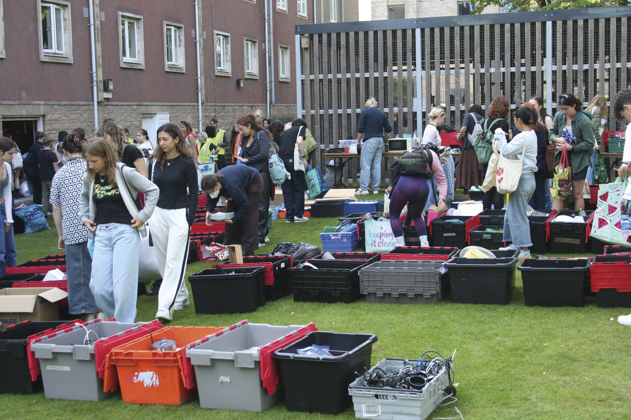 Rows of containers, open to display wares with groups of students rummaging through them.